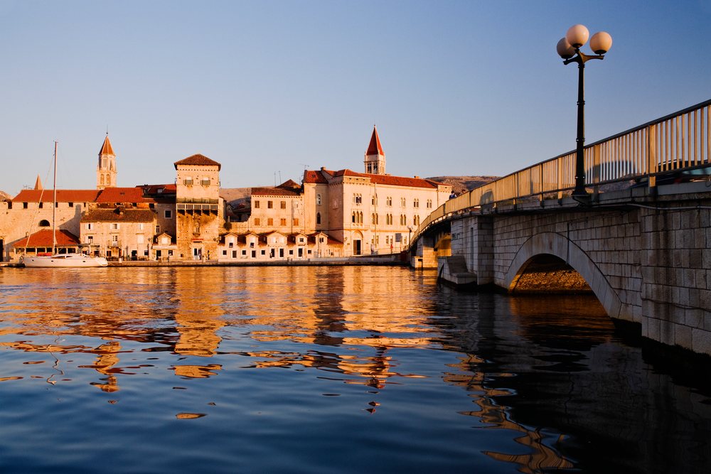 Town of Trogir reflects on water with bridge and historic buildings, Dawn, Croatia.