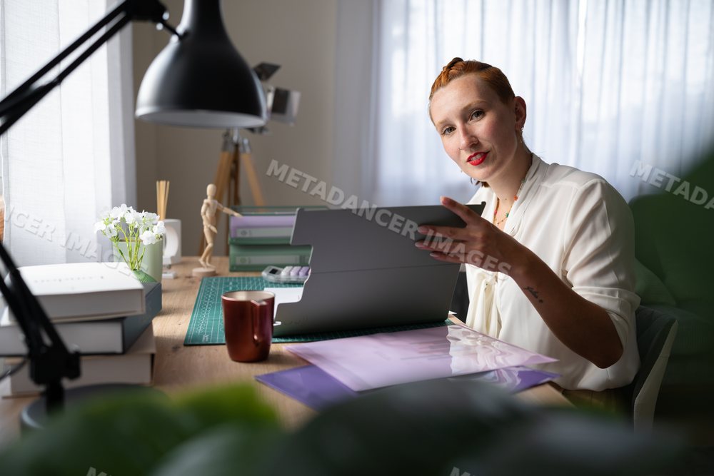 A white woman works from home using a tablet