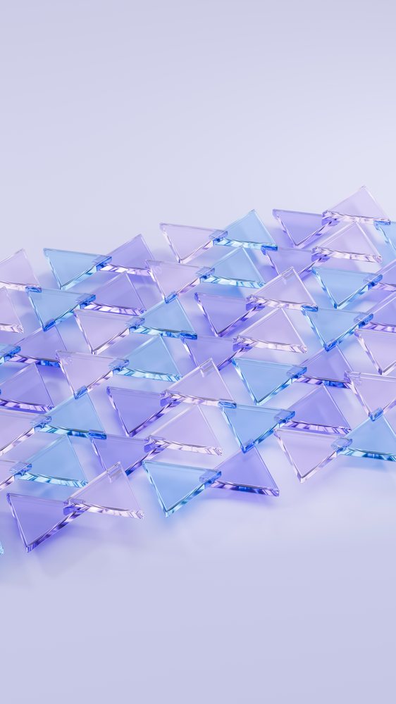 Transparent blue and purple triangular glass pieces form an overlapping symmetrical pattern with light reflections on a smooth surface.