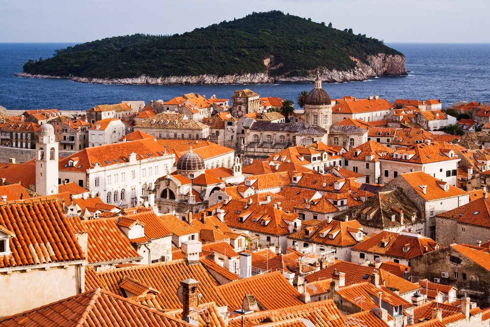 View of Dubrovnik's old city with red tile roofs and Lokrum Island beyond in the Adriatic Sea, Croatia.