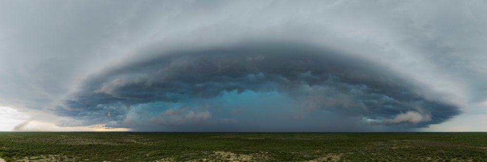 Supercell storm with dark swirling clouds and a tornado forming over flat green land in Tornado Alley, Storm Chasing, Weather, Environment, Del Rio, Texas, USA.