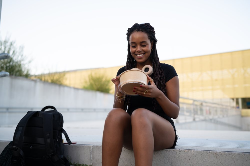 A young woman happily eating outdoors in an urban setting, Santiago De Compostela, Spain.