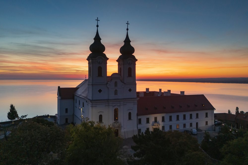 Benedictine Abbey of Tihany with twin towers at sunset overlooking a tranquil lake, Cityscape, Hungary.