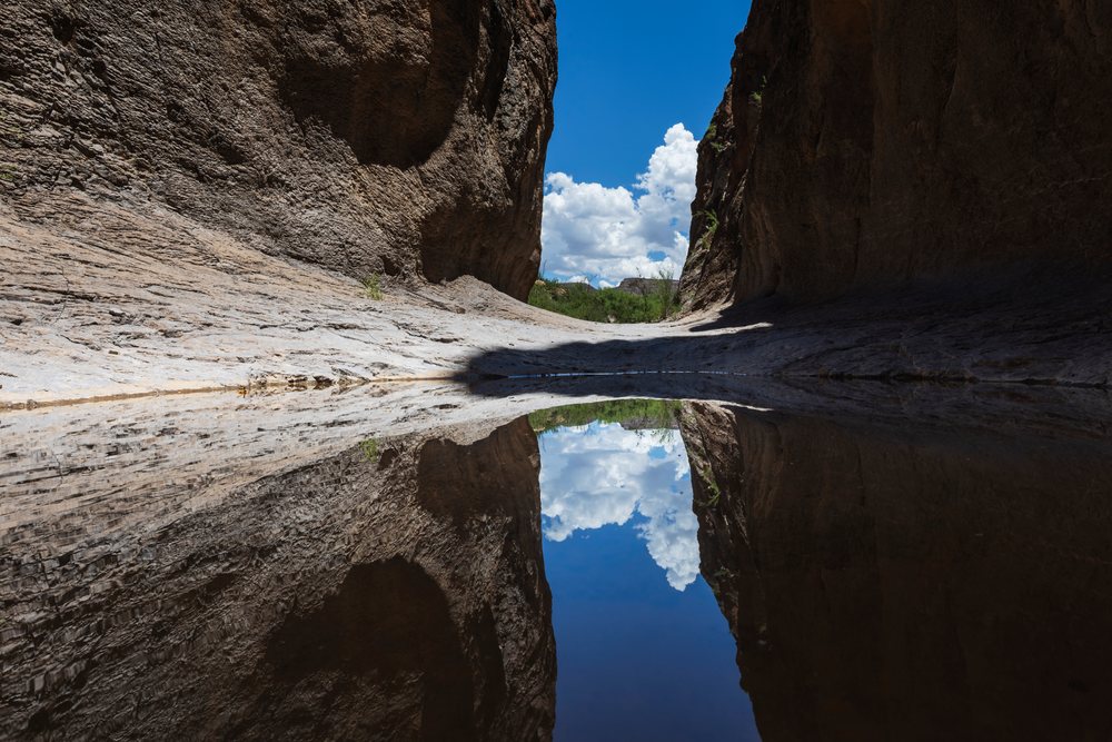 Slot canyon with rock walls reflecting blue sky and clouds in still water, Landscape, Wildlife, Bigbend State Ranch, Lajitas, Texas.