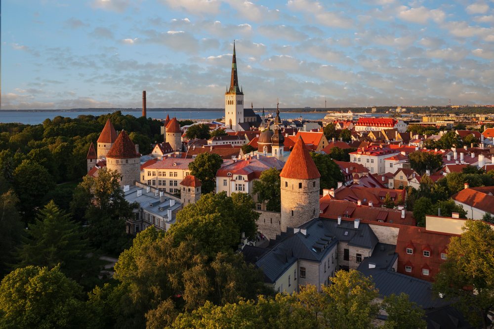 Tallinn Skyline at Sunset showing historic towers with red roofs and a white church steeple, overlooking the Baltic Sea, cityscape, Estonia, Baltic States.