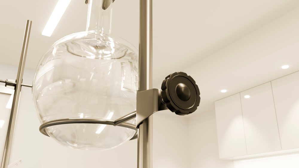 Round bottom glass flask secured by a metal clamp stand in a laboratory setting with scientific equipment.