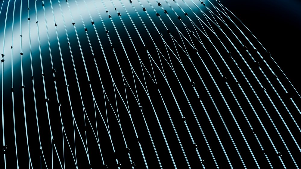 Curved fiberglass cables with metal connectors form an abstract architectural pattern under blue lighting.