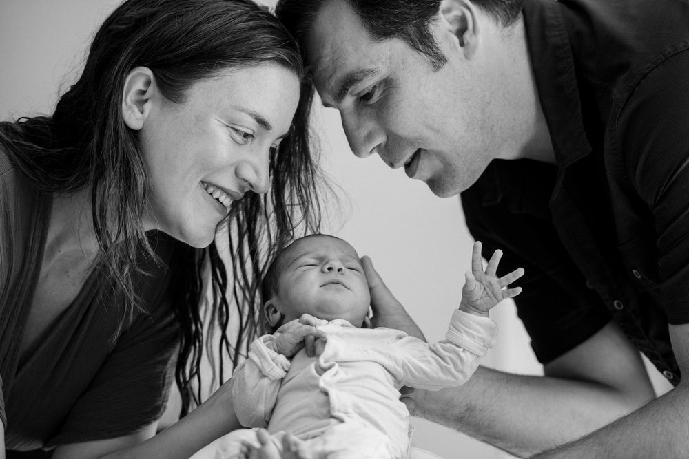 Newborn baby held by smiling parents sharing a tender moment indoors, USA.