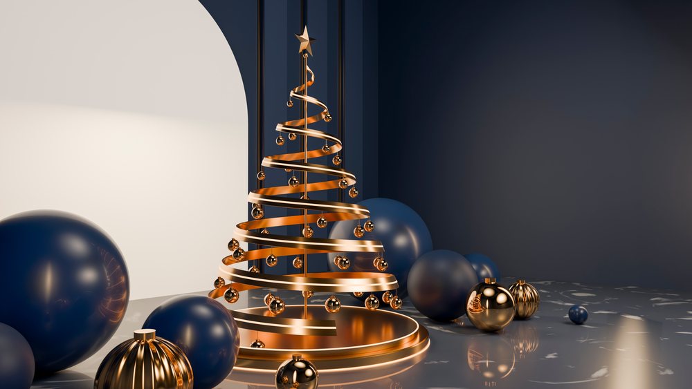 Metallic gold spiral Christmas tree decorated with gold spheres beside dark blue and gold ornaments on a reflective marble floor under soft arch lighting.