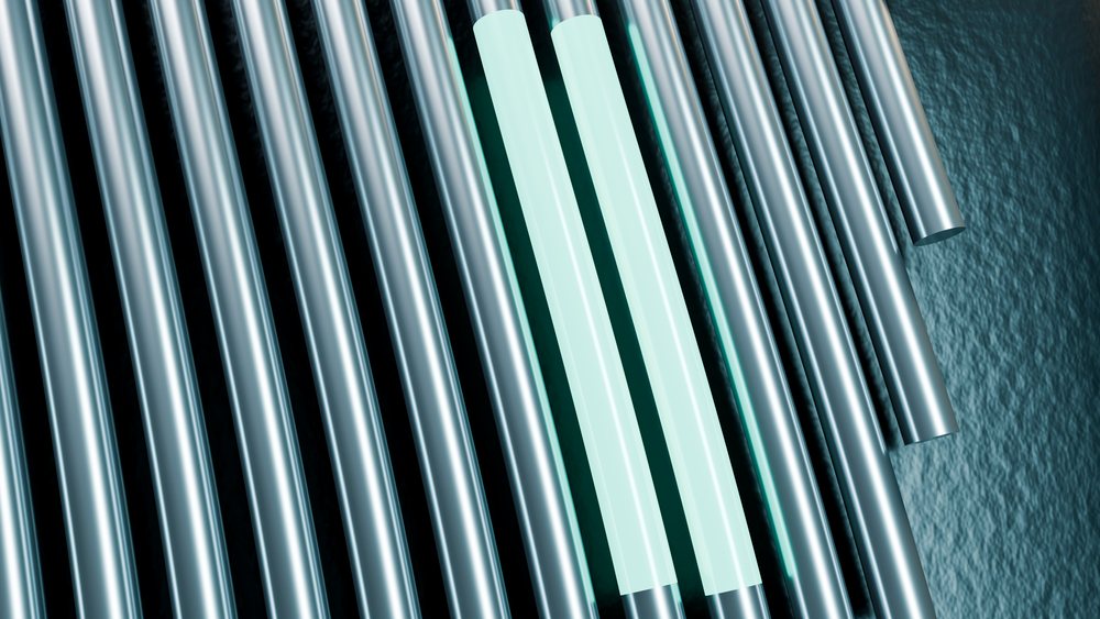 Metal tubes arranged in parallel on an industrial surface, highlighting metallic textures and reflective properties.