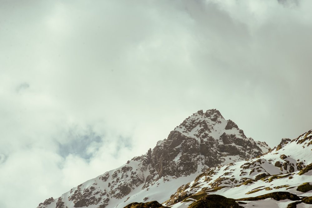 Snow-covered rocky mountain peak under overcast sky, mountaineering, climbing, landscape, Spain.