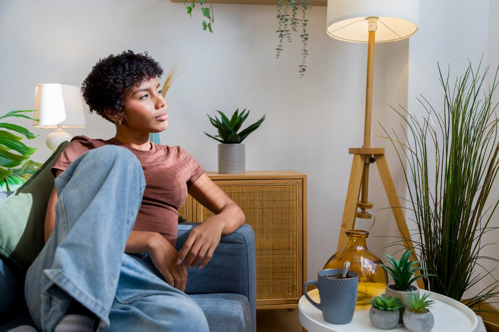 Young woman in casual clothing relaxing on a blue fabric sofa in a modern living room.