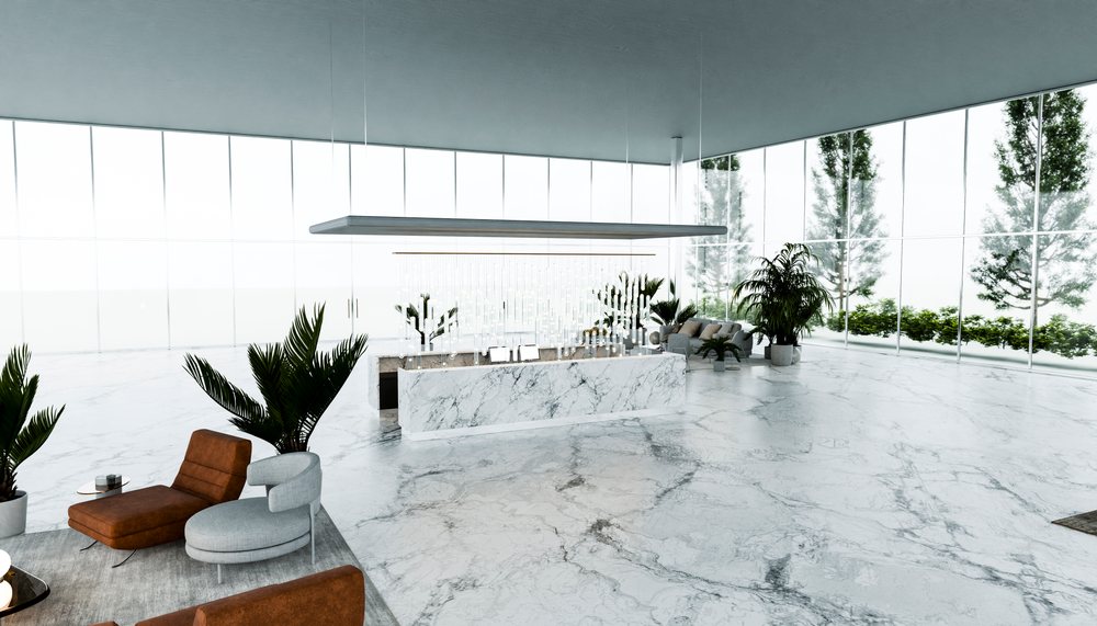 Modern lounge interior with marble counter and floor, large glass walls, seating including brown and gray chairs, and green potted plants.