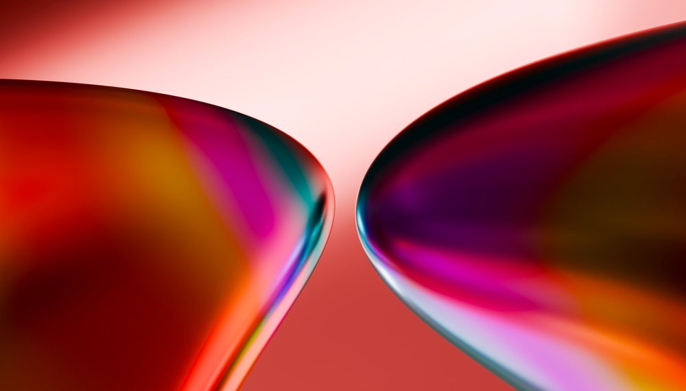 Abstract close-up of two curved colorful glass shapes with reflections on a red gradient background.