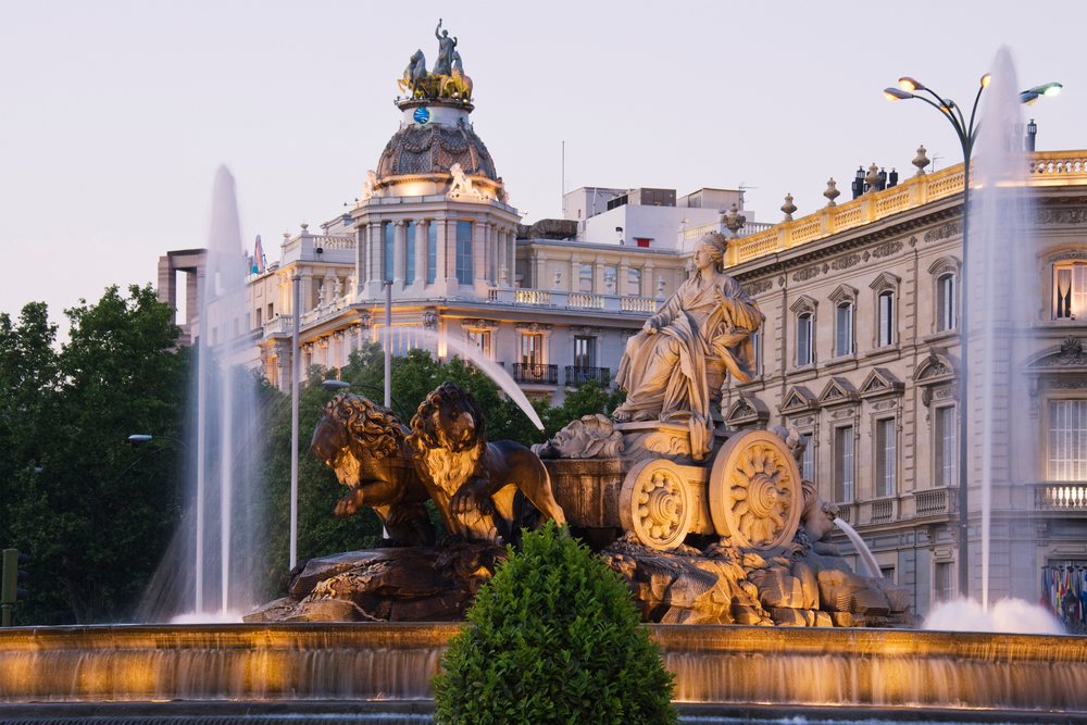 Cibeles Fountain with Mariblanca statue and decorative lion sculptures cityscape at sunset, Madrid, Spain.