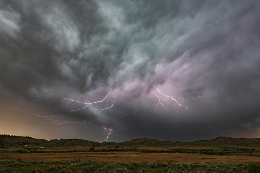 Lightning bolts strike from storm clouds above rural hills in the Great Plains region of the, Gillette, Wyoming, USA.