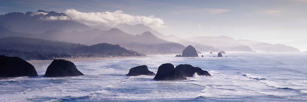Rock formations rise along the misty Pacific Ocean coastline at Ecola State Park, Oregon, Ecola State Park Oregon, USA.