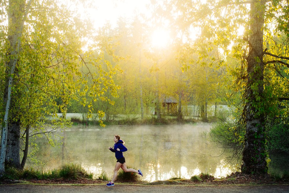 Woman jogging along a path by a misty lake, Bainbridge Island, Wa, USA.
