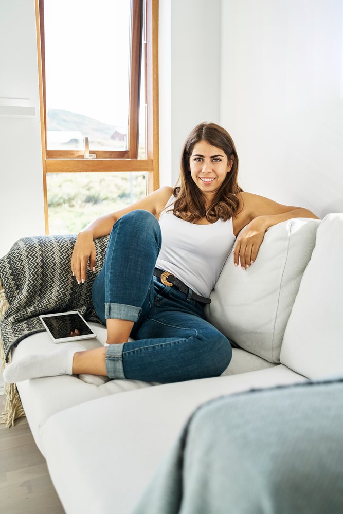 A woman relaxing on a white sofa in a bright living room