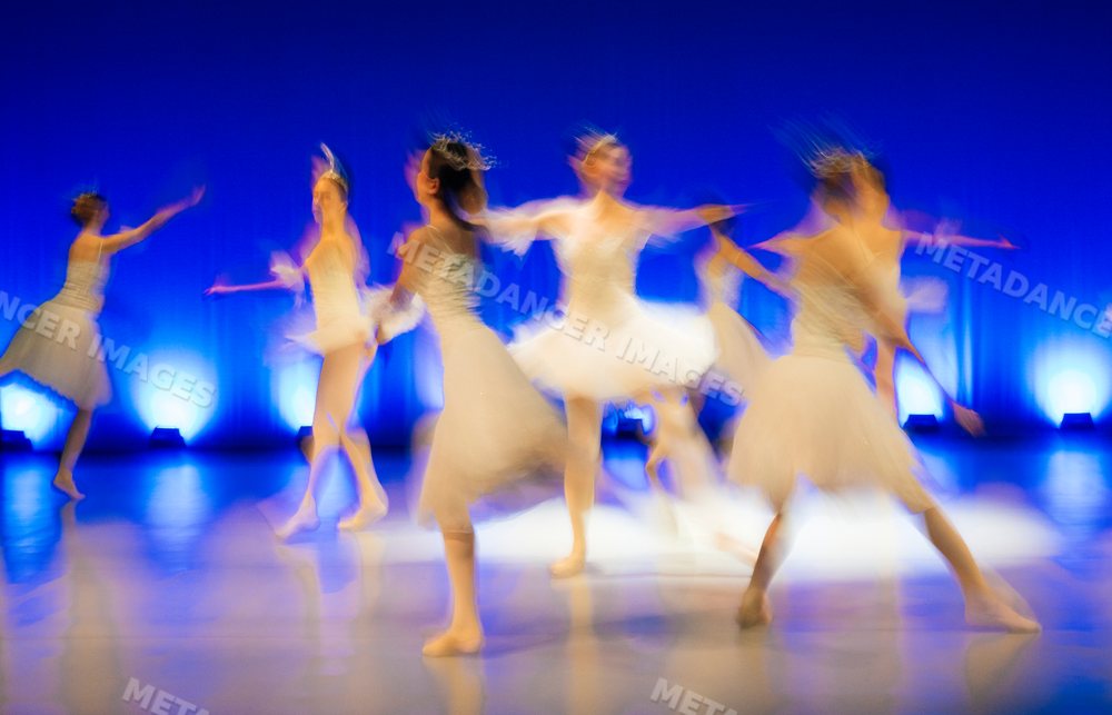 Ballet dancers perform holiday ballet on stage in white tutus