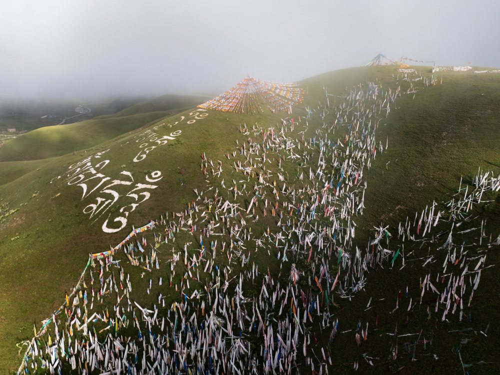 Prayer Flags decorate a grassy hill in Kham Tibet on a misty morning, Tagong, Sichuan Province, People's Republic of China.