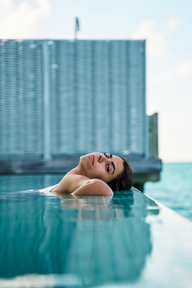 A white woman relaxes at the edge of a swimming pool