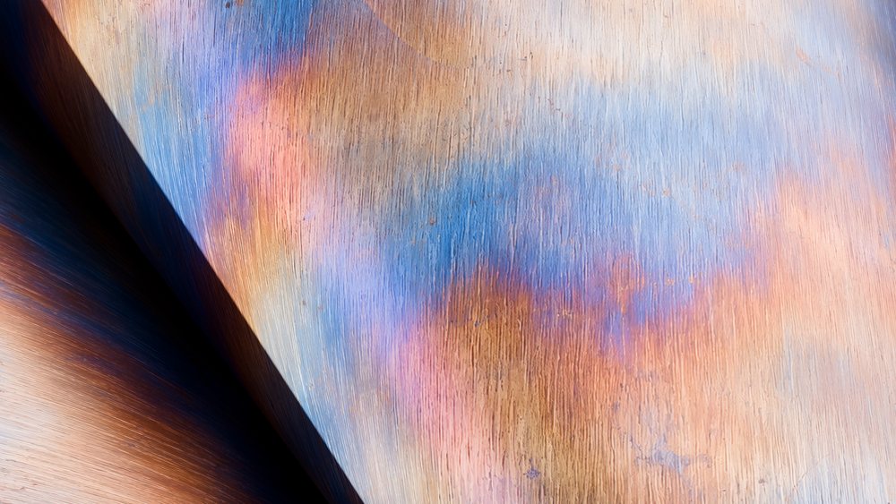 Close-up of a metal surface exhibiting colorful oxidation and rust textures with intricate details.