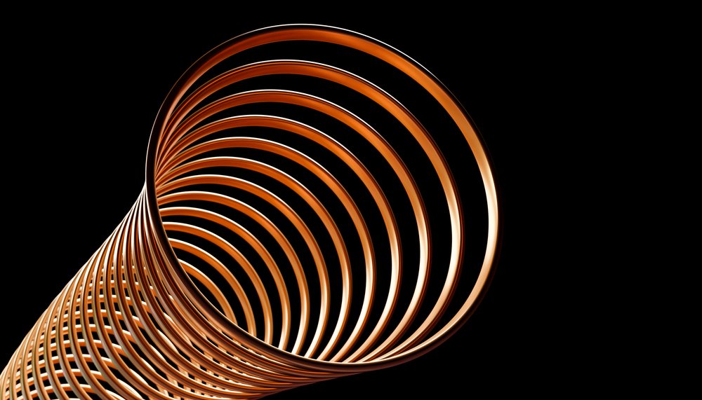 Close-up of a metal helical spring with copper-colored coils isolated on a black background showing its smooth reflective surface.