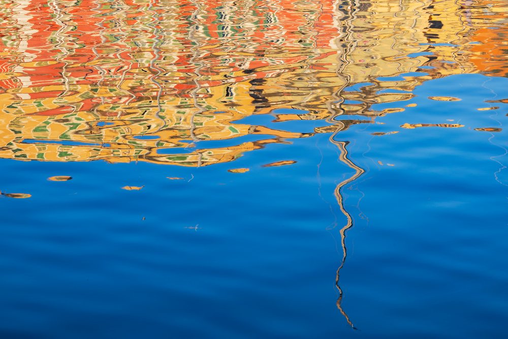 Colorful, distorted Reflections of buildings ripple on the calm water surface, Travel Photography, Bastia, Corsica, France.