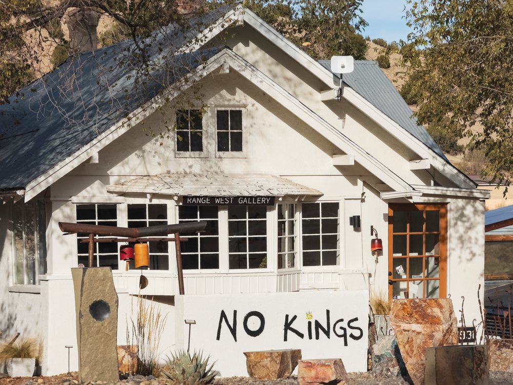 Range West Gallery building with rock sculptures and 'NO KINGS' signage outdoors, USA under sunlight and blue sky, Americana, Historic, Madrid, New Mexico.