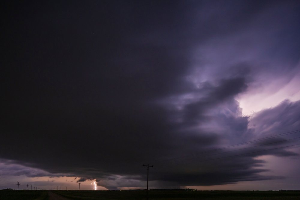 Wedge Tornado touches down under a dark Supercell with Lightning striking over a flat rural landscape in North Dakota at night, Storm Chasing, USA, Tornado Alley, Great Plains.