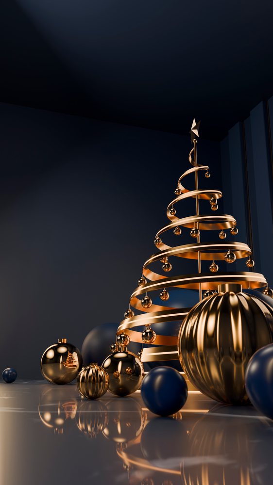 Metallic gold spiral Christmas tree with gold and blue spherical ornaments on a reflective surface inside a dark blue room.