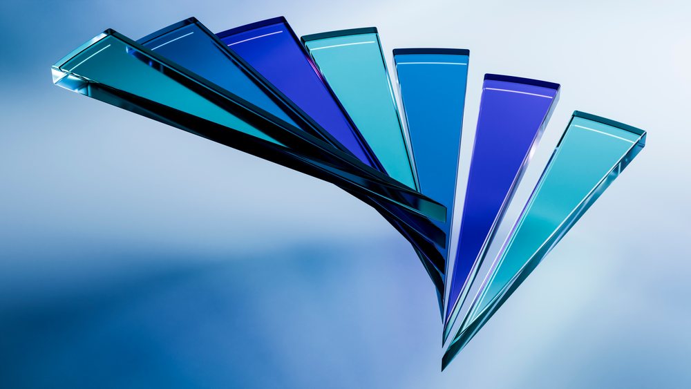Blue glass sculpture features geometric shapes with a shiny surface and a color gradient in blue tones on a light background.