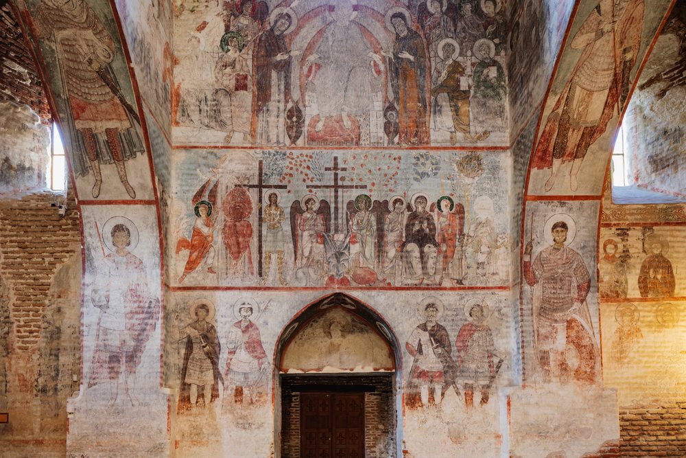Medieval religious fresco paintings of Christian saints and holy figures adorn the walls and arches inside Tsagveri Timothesubvani Monastery, Georgia.
