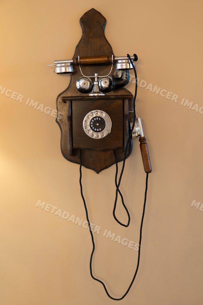 Retro wooden rotary dial telephone with metal bells mounted on wall