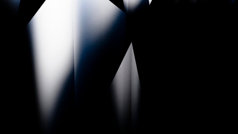 abstract geometric shapes formed by light and shadows creating gradient contrasts on black background.
