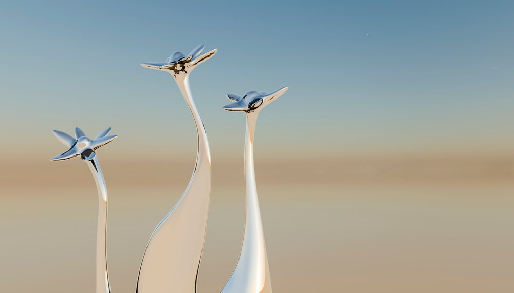 Three tall silver abstract sculptures stand against a blue sky