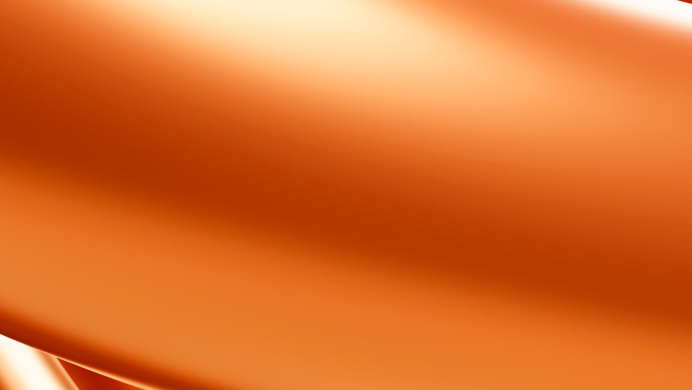 Close-up of smooth vibrant orange fabric with silky folds showing detailed textile texture.
