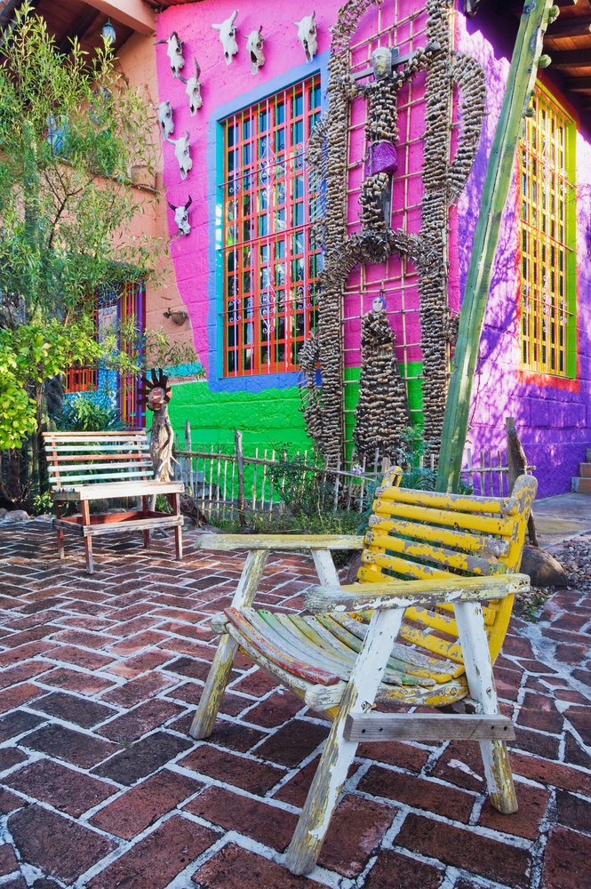 Wooden chairs and animal skull decorations displayed outside a colorful house with brick pavement, San Miguel de Allende, Mexico.