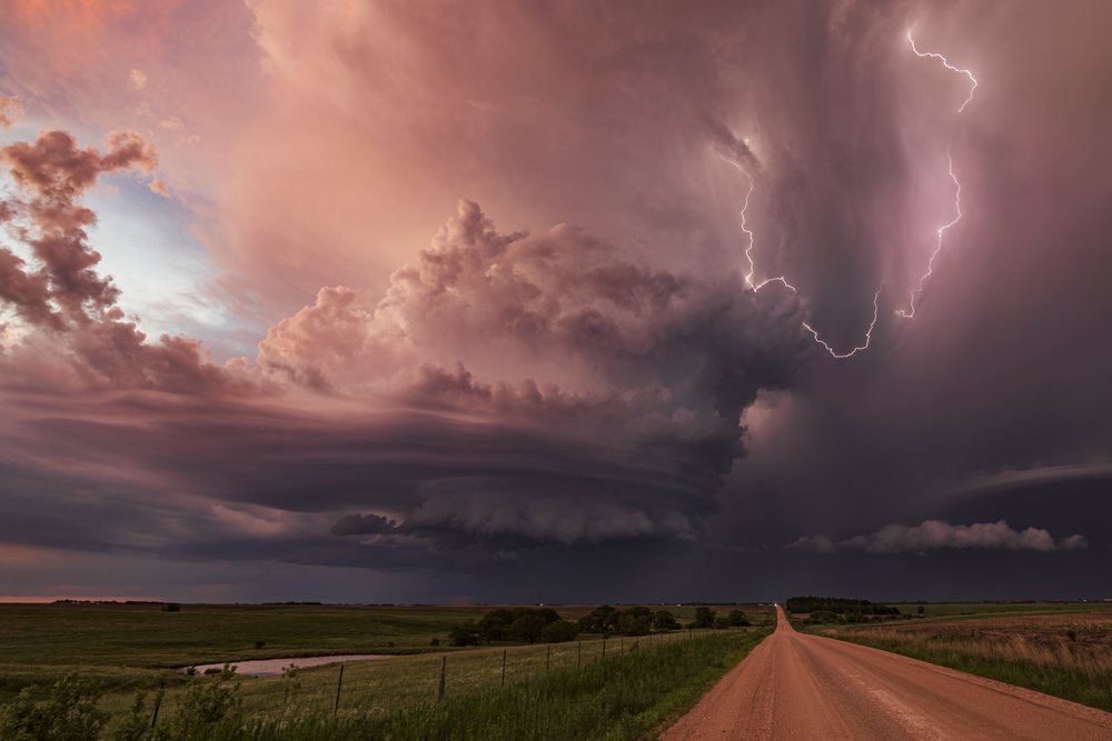 Supercell thunderstorm with Lightning bolt over a dirt road in rural Nebraska's Great Plains at Sunset, Storm Chasing, Weather, Environmental, Jansen, USA.