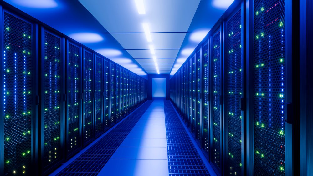 Indoor data center corridor features rows of server racks with blue ambient lighting and illuminated indicator lights.
