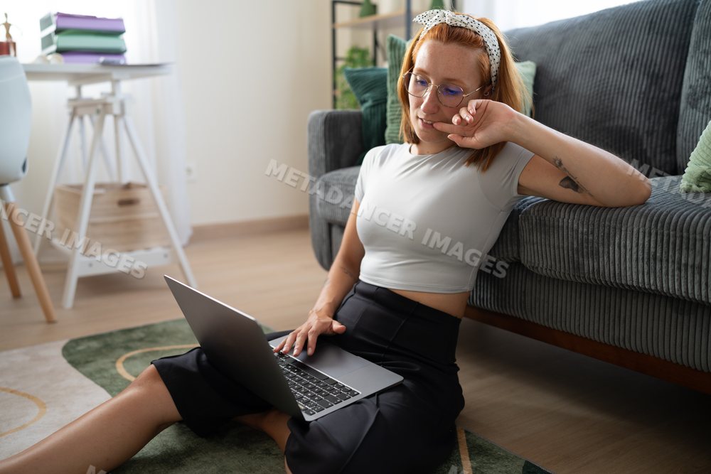 White Woman sitting on floor working on laptop