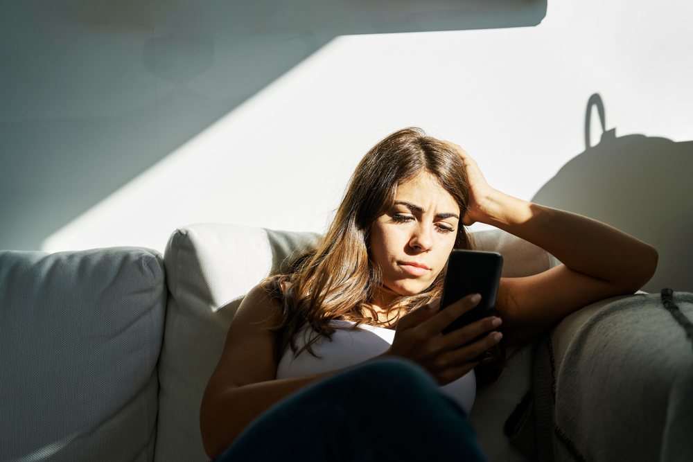 White Woman sitting on a sofa using a smartphone at home in Iceland