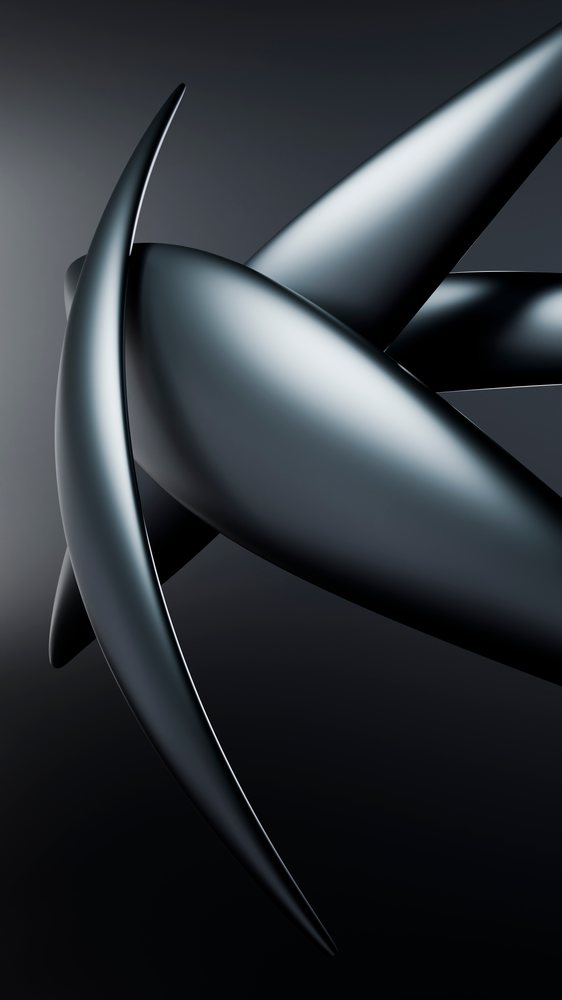 Black abstract sculpture with smooth metallic finish and curved shapes displayed in a dark studio setting.