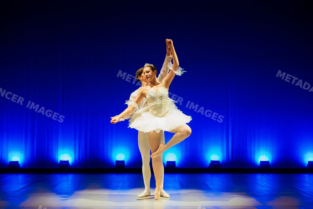 Male and female ballet dancers perform a graceful pose