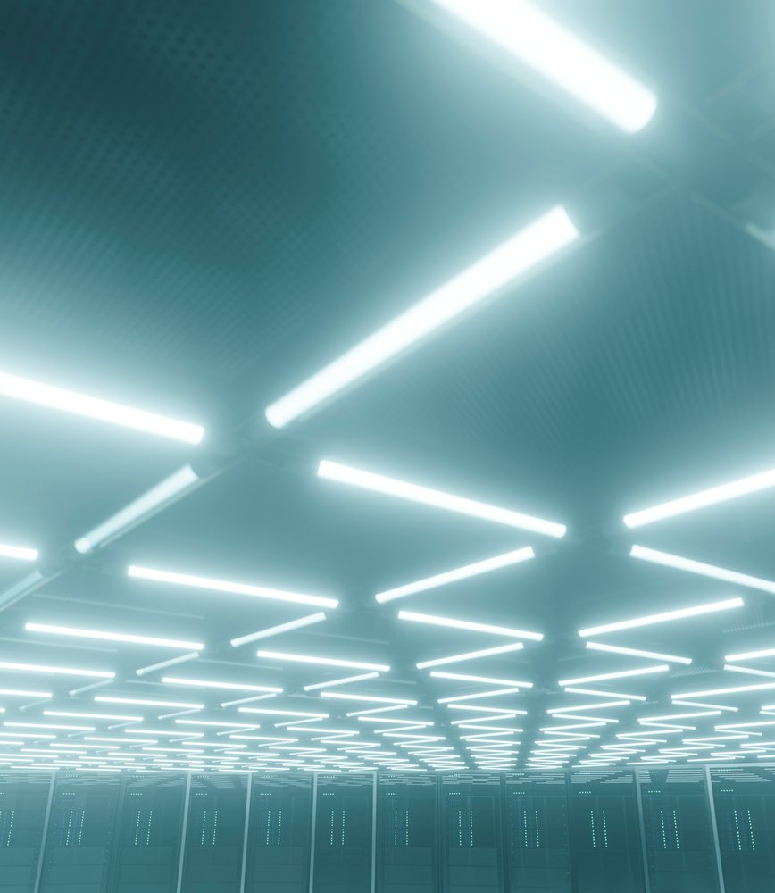 server racks under ceiling lights in a data center.