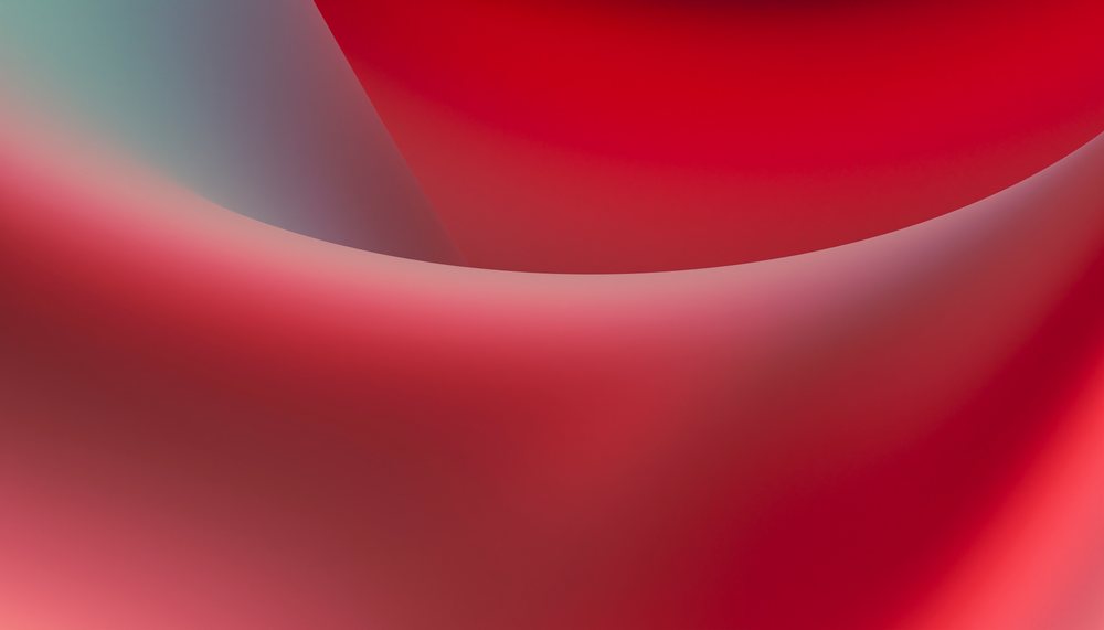 Close-up photo of red silky fabric with smooth curved folds in a studio setting.