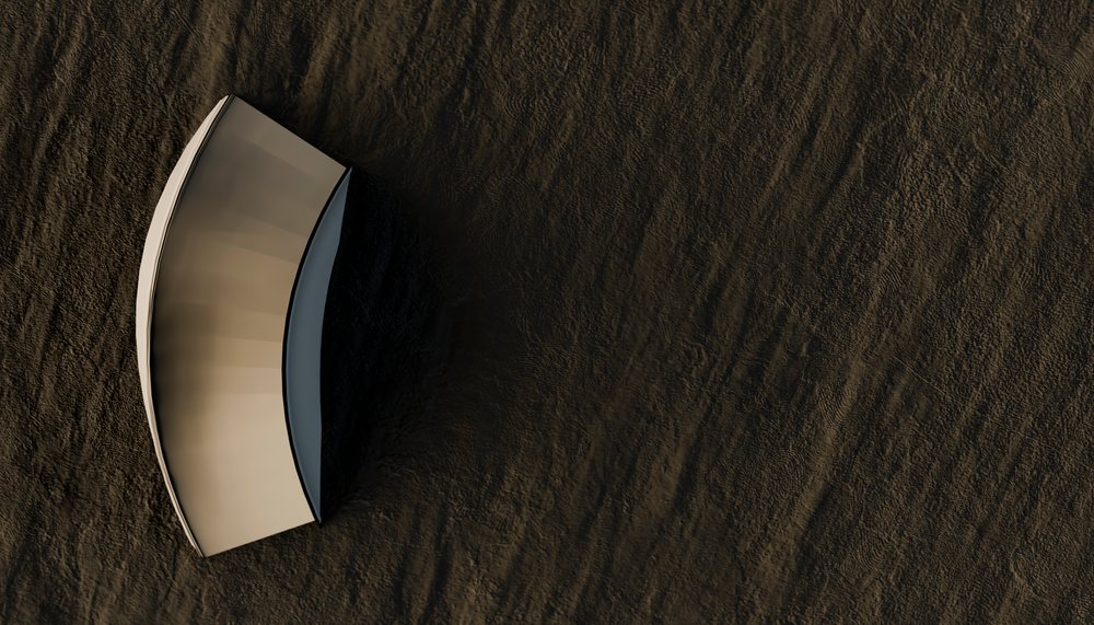 Inverted wooden boat resting on textured beach sand without water, viewed from above.