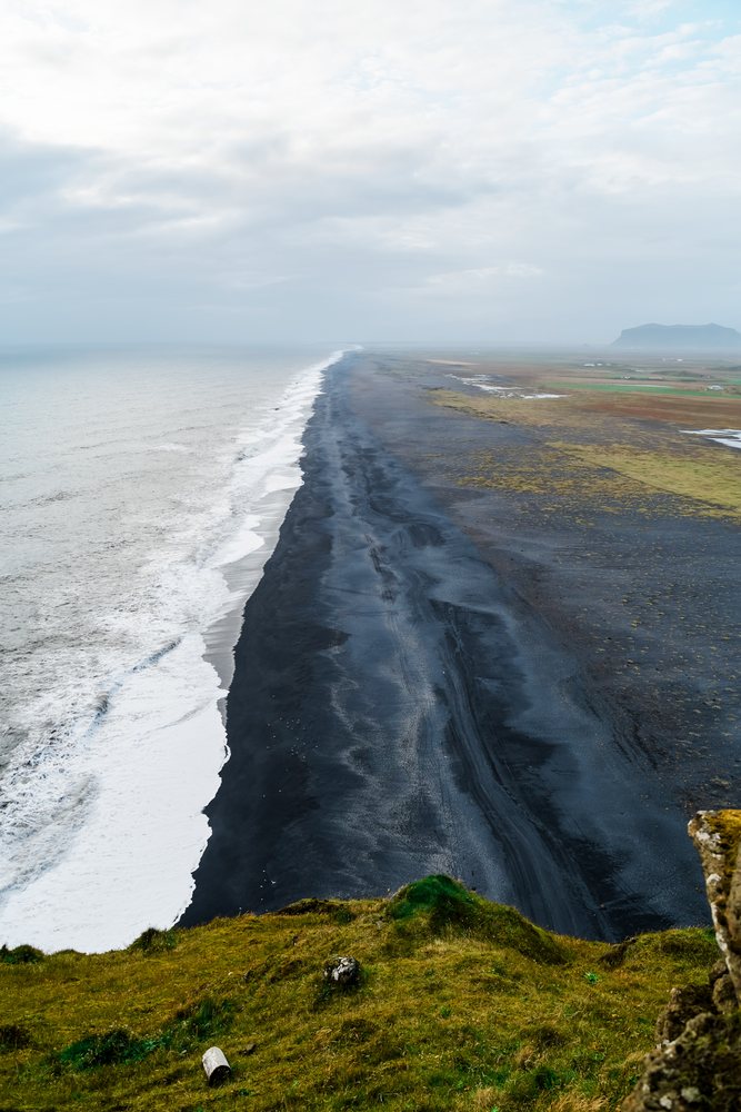Aerial view of the black sand beach and crashing waves in a beach