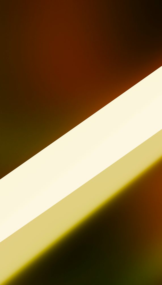 Diagonal beam of bright white and yellow light against a dark background creating abstract contrast and illumination.